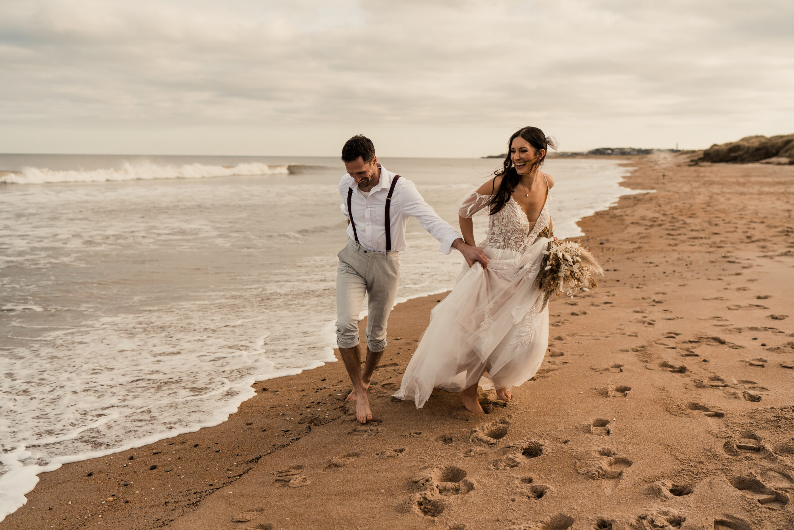 bride and groom running on northumberland beach